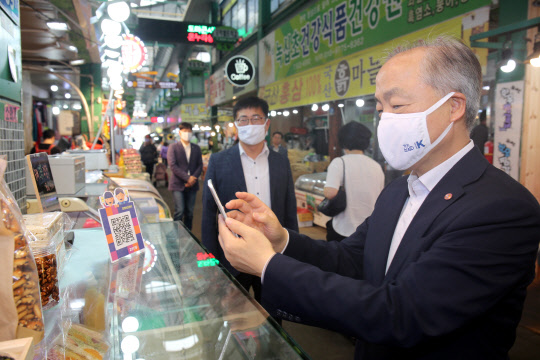 조봉환(오른쪽) 소상공인시장진흥공단 이사장이 지난달 30일 대전 도마큰시장에서 상품을 구매한 후 '모바일 온누리상품권'으로 결제하고 있다.   소진공 제공